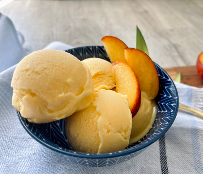 https://mirjamskitchenyodel.com peach ice cream close up with fresh peach slices