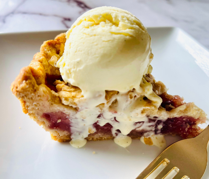 https://mirjamskitchenyodel.com strawberry rhubarb pie slice with vanilla ice cream