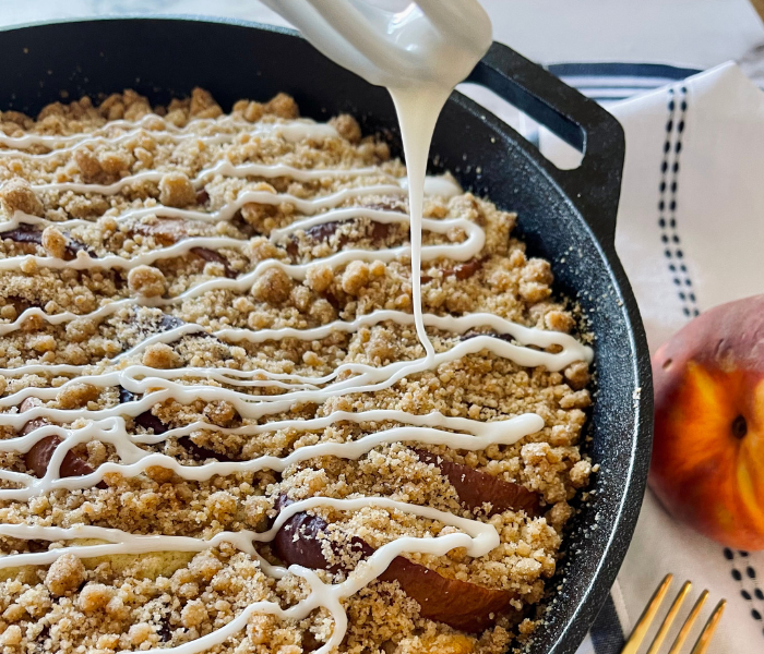 https://mirjamskitchenyodel.com adding glaze to the peach crumb coffee cake