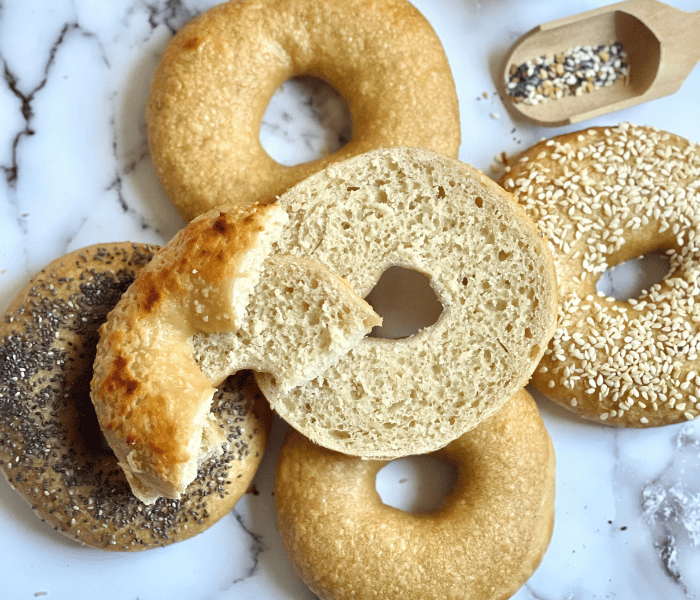 https://mirjamskitchenyodel.com homemade bagels with a cut in half bagel on top